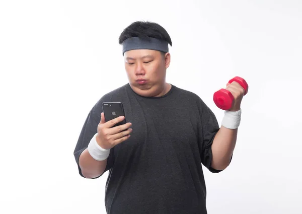 아시아인 재미있는 선수가 덤벨을 가지고 운동을 백지에 고립된 스마트폰을 사용하는 — 스톡 사진
