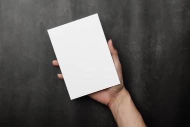 El ele tutuşan davetiye maketi, boş tebrik kartı şablonu. Düz yatış, üst görünüm.