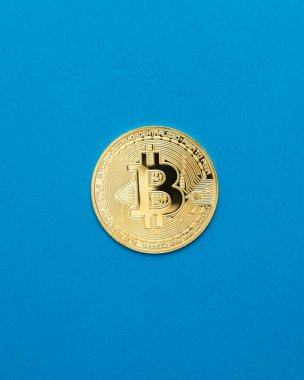 Parlak, mavi arka plan merkezli tek bir Bitcoin parasının en üst görüntüsü. Kripto para piyasası, dijital finans, engelleme teknolojisi ve sanal yatırım için minimalist kavramsal çekim.