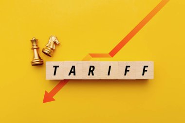 Tahta bloklar TARIFF 'i altın satranç taşları ve sarı arka planda aşağı doğru kırmızı bir okla heceliyor. Stratejik ticaret politikası, ekonomik etki ve uluslararası iş rekabetini temsil ediyor.