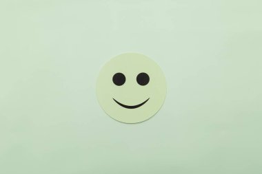 Nane yeşili arka planda gülen bir yüzü olan açık yeşil kağıt çemberi. Müşteri memnuniyeti, akıl sağlığı, pozitiflik ve neşe için minimalist bir kavram. Geniş kopyalama alanı olan düz uzanmış.
