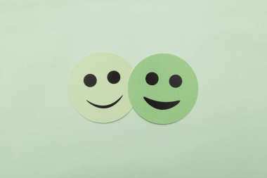 Nane yeşili arka planda iki mutlu yeşil gülen yüz. Akıl sağlığı, dostluk, takım çalışması ve pozitif ilişki kavramları için mükemmel. Geniş kopya alanına sahip minimalist düz uzanma biçimi.