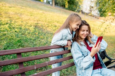 Genç bir anne ve 7 yaşındaki kızı telefonda ortak bir fotoğraf çekiyorlar.