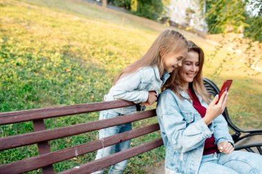 Genç bir anne ve 7 yaşındaki kızı telefonda ortak bir fotoğraf çekiyorlar.