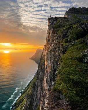 Kuzey Norveç 'te Senja adası üzerinde gün batımı, çerçevenin ortasında Hesten Dağı.