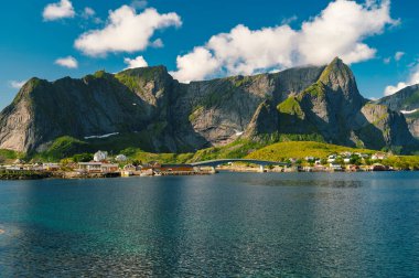 Reine balıkçı köyünde güzel, renkli, aydınlık bir gün ve Lofoten takımadalarında arka planda dağlar, Norveç. 