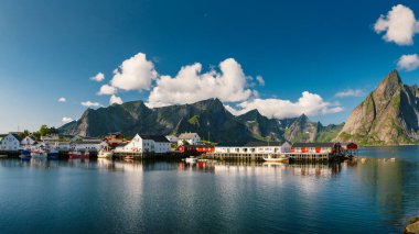 Reine balıkçı köyünde güzel, renkli, aydınlık bir gün ve Lofoten takımadalarında arka planda dağlar, Norveç. 
