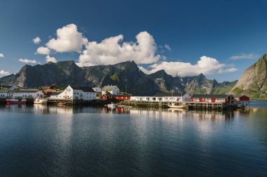Reine balıkçı köyünde güzel, renkli, aydınlık bir gün ve Lofoten takımadalarında arka planda dağlar, Norveç. 