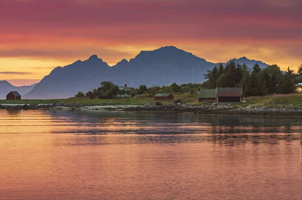 ロフトテン島のノルウェーのフィヨルドの上にカラフルな夕日と古典的な赤い木製の小屋を背景に — ストック写真