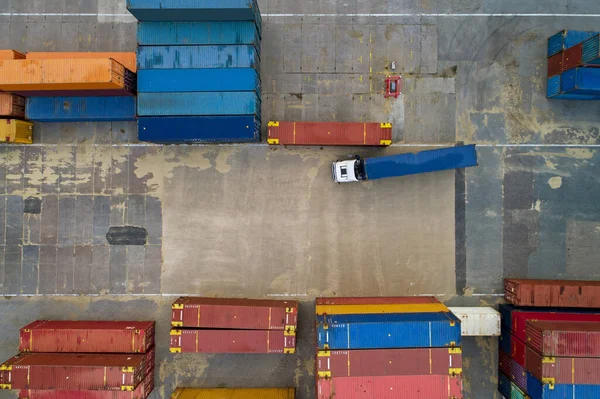 Port area with ships, metal containers and heavy trucks.