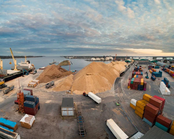 Port area with ships, metal containers and heavy trucks.