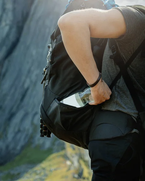 Backpacker man hiking in mountains with water bottle in his backpack side pocket
