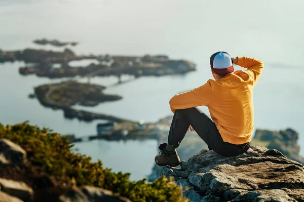 在挪威长途跋涉之后 身披橙色上衣的男子坐在山顶上 — 图库照片