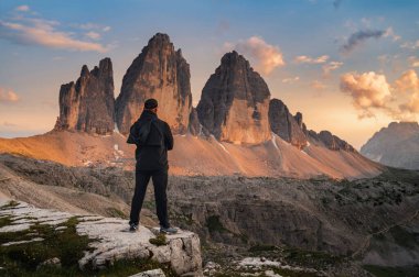 Gün batımında Tre Cime di Lavaredo 'nun üç tepesi ve ön planda duran erkek.