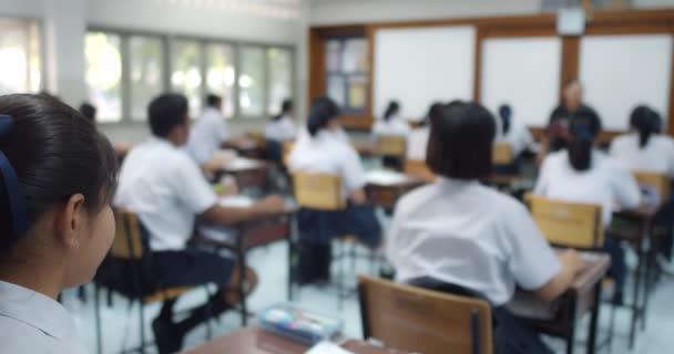 身穿白衣的亚洲高中生的动作缓慢 他们主动举手回答老师在课堂上问他们的投影仪屏幕上的问题 — 图库视频影像