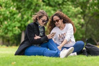 Telefonla konuşuyor, çalışıyor, parkta dinleniyor, çimlerin üzerinde oturuyor..