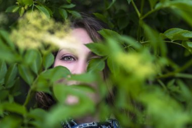 Genç kadın bitkilerin arasında poz veriyor, izliyor ve kamufle oluyor..