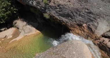 Katalonya, İspanya 'da güneşli bir günde şelale manzarası ve küçük yeşil havuz