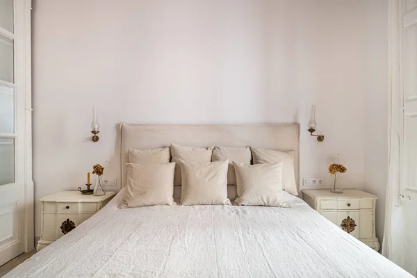 Interior de quarto brilhante, cama acolhedora com linho bege, flores secas em uma mesa de cabeceira. Estilo retro e vintage. — Fotografia de Stock