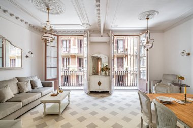 Yemek masası, kanepe, fayans zemin, klasik avizeler ve balkonlarla retro tarzı oturma odasının önü.