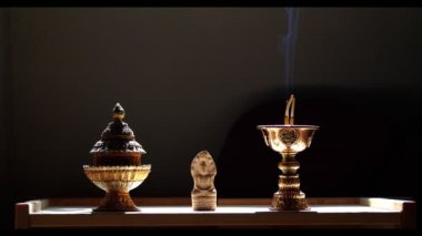 Tütsü tutacağı ve yanan çubuğu olan küçük Buda heykeli..