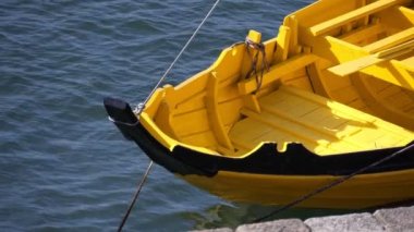 Sarı teknenin ön tarafı. Kaliteli ahşap tekne limanda suda yavaşça sallanır..