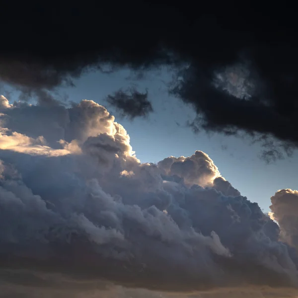 Confrontation of light and darkness. Clouds lighted with sun versus dark overhanging heavy clouds. Dramatic sky at sunset.