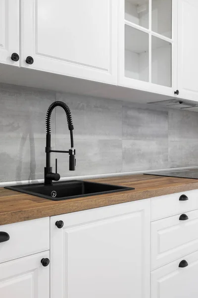 Einfache und elegante Küche mit Holzarbeitsplatte, weißen Schränken, Schubladen und schwarzem Spülbecken. — Stockfoto