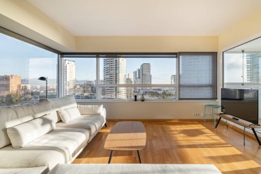 Güneşli oturma odası, sabahları büyük pencereli, panoramik manzaralı modern binalı..