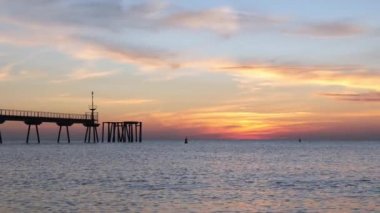Güneş doğmadan birkaç dakika önce sabah erkenden. Şafak vakti duba ile denize açılacak. Mavi gökyüzü pembe ve turuncu tonlarda boyanmıştır..