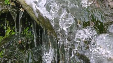 Arka bahçedeki buzlarla kaplı bir dalda düşen su. Dağ nehri kışın.