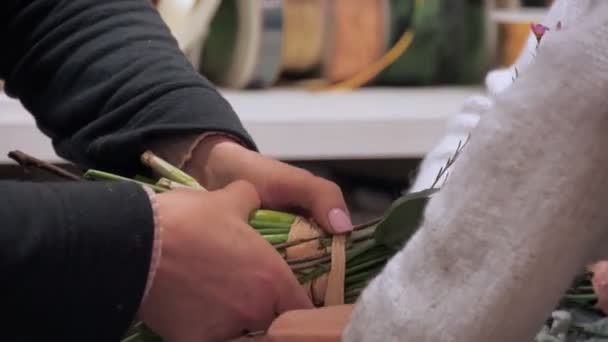 Крупним планом руки двох флористів, зав'язаних великим букетом зі стрічкою в квітковому магазині . — стокове відео