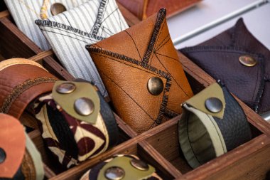 El yapımı cüzdanlar ve bilezikler, deri ve kumaştan yapılmış, metal perçinler ile bir mağaza rafında. Moda aksesuarı.