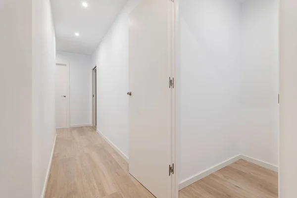 Quarto pequeno vazio com paredes brancas e corredor que conduz a outras salas. Apartamento após renovação. — Fotografia de Stock