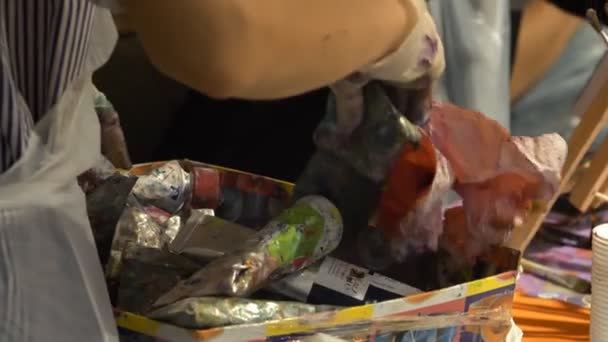 Umělec hledá trubici požadované olejomalby v krabici mezi použité trubky. — Stock video