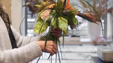 Çiçekçi gelin buketi yapıyor. Sahne arkasında çalışma zamanı. Kadın bir buket al ve ondan biraz bitki kes.