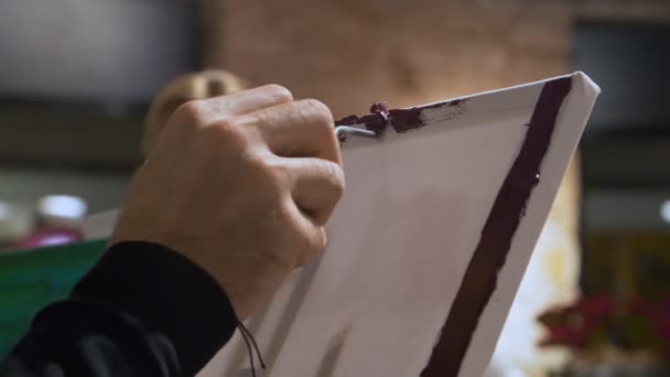 Мужчина рисует рамку картины масляными красками и мастихином. Занятия живописью в художественной школе. — стоковое видео