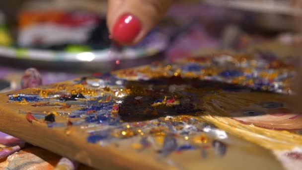 Mujeres mano espolvorea lentejuelas decorativas rojas en el cuadro pintado con pinturas al óleo de colores. — Vídeos de Stock