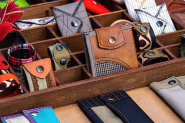 El yapımı cüzdan ve bilezikler, deri ve kumaştan yapılmış, metal perçinli, bir mağaza rafında. Moda aksesuarı.