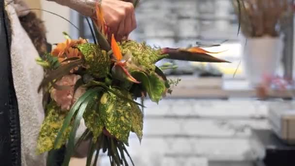 Florist gör en komposition i en blomsteraffär. Lägga in lite grönt i en brudbukett. — Stockvideo