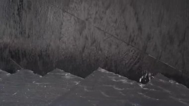 Su merdivenlerden aşağı akıyor ve yansımalı siyah taş bir duvar. Şehirde modern bir çeşme