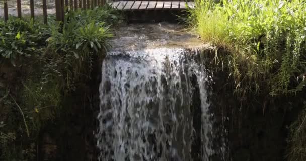 村の山の川のストリーム上の木製の橋。水は石の壁を通って行く. — ストック動画