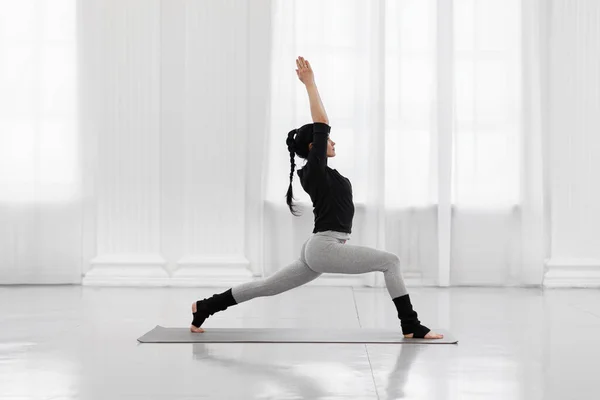 Krigare jag poserar. Vacker ung asiatisk kvinna som utövar yoga poserar på grå matta i yogastudion. — Stockfoto