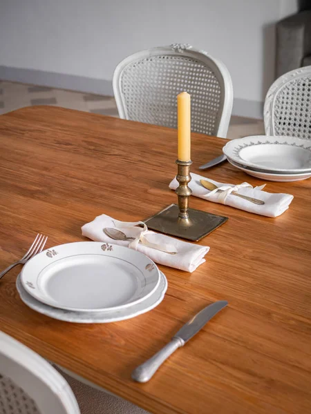 Houten tafel voor twee personen, met borden, bestek en oude kandelaar met kaars. Interieur van woonkamer ingericht in vintage stijl. — Stockfoto