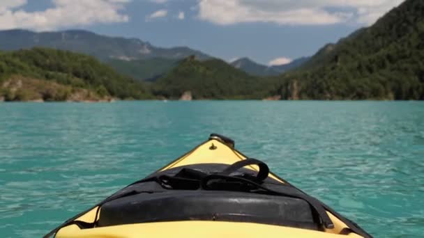 Fronte di kayak giallo su un lago di smeraldo con sfondo di montagna e cielo. Focus selettivo. — Video Stock