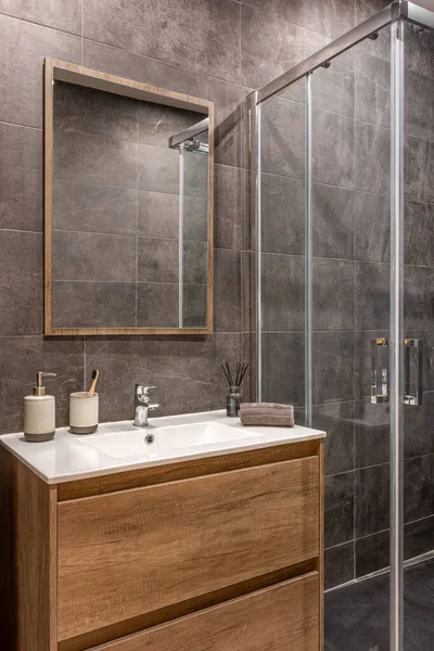 Moderne gerenoveerde badkamer met douche zone. Houten onderstel met witte wastafel en spiegel. Stockafbeelding