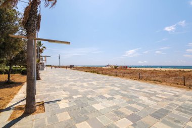 Ağaçlı yaya geçidi ve Barselona, İspanya 'daki Castelldefels plajına yakın birkaç kişi. Mavi gökyüzüyle güneşli bir yaz günü.