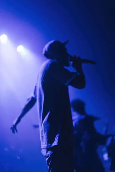 Cantante borroso con micrófono en el escenario con rayos azules de luz. Fondo abstracto del concierto o festival de música. —  Fotos de Stock