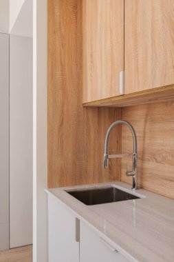 Modern musluk ve ahşap dolaplarla şık bir mutfakta lavabo. Yenilenmiş dairede minimalist stil iç mekan.