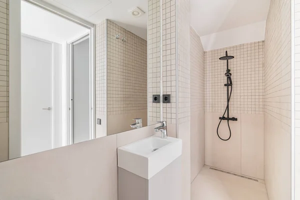 Intérieur de salle de bain moderne avec carrelage beige, douche et petit lavabo — Photo